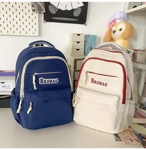 Detail view of RKDBAG backpacks in navy and beige showing textured nylon and zip pockets