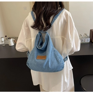 Dettaglio dello zaino in denim blu con patch in pelle marrone in un contesto casual