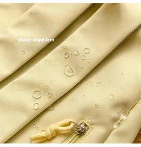 Detailed view of light yellow water-repellent fabric with water droplets and matching zipper