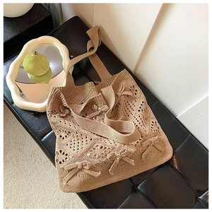 Détail du sac cabas en maille beige avec motif ajouré et ornements en nœuds
