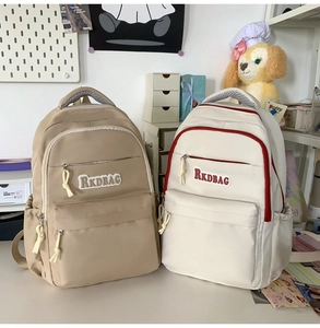 Detail view of nylon travel backpacks in khaki and white colors with multiple pockets