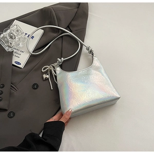 Holographic silver PU crossbody bag with pearl heart charm on grey suit background