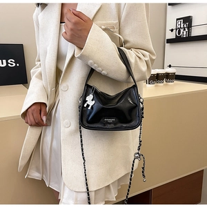 Détail du sac polochon en cuir verni noir avec chaîne argentée et breloque cheval