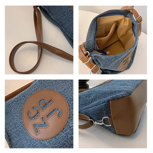Detail view of denim tote bag showing interior lining, strap adjustment, and leather bottom