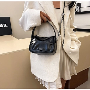Détail du sac polochon en cuir brillant noir avec chaîne et breloque chien