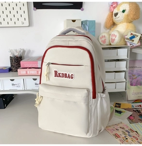 Detail view of off-white canvas backpack featuring red zipper trim and RKDBAG printed logo