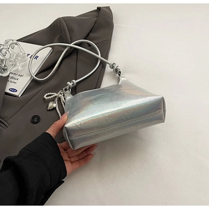 Detail of silver laser bucket bag featuring pearl heart charm and crinkled texture