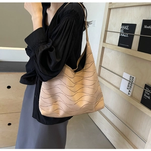 Detail of beige hobo tote bag featuring a unique wavy textured pattern and soft leather