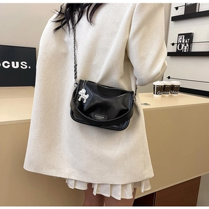 Dettaglio borsa nera lucida con catena argento e ciondolo a forma di piccolo pony