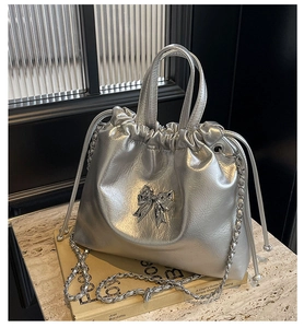 Détail du sac seau métallisé argenté avec texture brillante et nœud décoratif