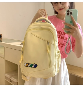 Close-up of a yellow nylon backpack with multi-layer zippers and AKDBAG patch