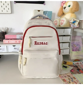 Detail of cream canvas backpack with red piping, RKDBAG embroidery and rope puller