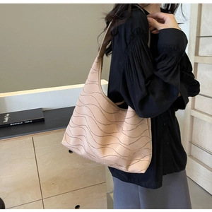 Close-up of beige shoulder bag featuring a 3D wavy textured pattern and crescent shape
