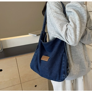 Dettaglio borsa tote in denim blu scuro con etichetta in pelle e cuciture rifinite