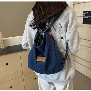 Dettaglio dello zaino in denim blu con etichetta in pelle e chiusura a coulisse