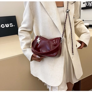 Vue détaillée du sac à bandoulière rouge foncé brillant avec chaîne et breloque cheval