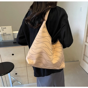 Detail of beige tote bag with wavy texture on shoulder of model in home setting