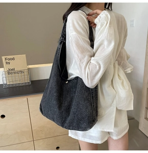 Détail du sac hobo en denim noir délavé robuste avec coutures apparentes et bouton pression