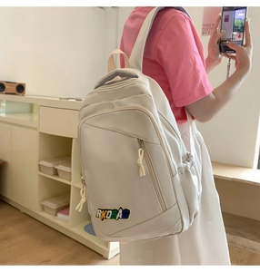 Side view of a cream-colored nylon backpack with RKOBAG embroidery for daily use
