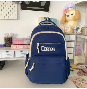 Detail of navy nylon backpack showing multiple pockets and RKDBAG embroidery on desk