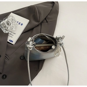 Silver metallic crossbody bag with pearl charm showing interior storage capacity