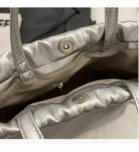 Détail du sac à main plissé argenté avec fermoir magnétique et doublure à chevrons