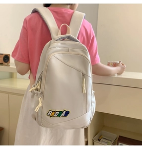 Close-up of beige nylon backpack featuring colorful AKDBAG embroidery and side pocket