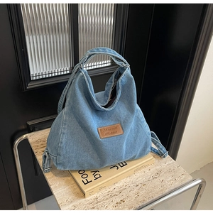 Dettaglio della borsa tote in denim blu con toppa in pelle marrone e cuciture di alta qualità