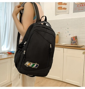 Detail of black student backpack featuring a colorful AKDBAG patch and breathable straps