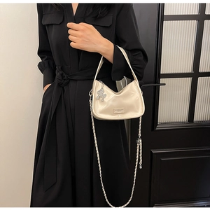 Détail du sac polochon blanc crème en cuir brillant avec pendentif cheval argenté