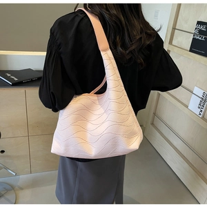 Macro detail of wave-textured pale pink tote bag showing premium material on a model