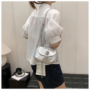 Details der silbernen Satteltasche mit mattem Leder und Kettengurt auf der Schulter