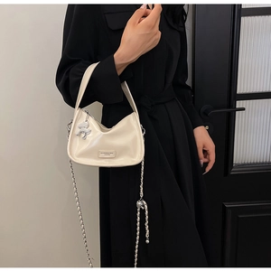 Détail du sac à main blanc crème brillant avec chaîne en métal et charm cheval argenté