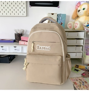 Detail of RKDBAG beige nylon backpack featuring front logo and knotted zipper pullers