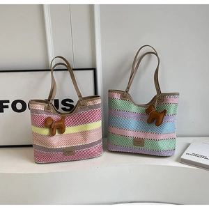 Dettaglio di borse tote in paglia a righe colorate con ciondolo a forma di cucciolo
