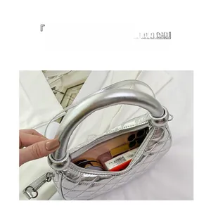 Detailed macro view of silver metallic crescent bag with quilted pattern and daily items