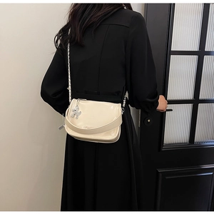 Détail du sac bandoulière en cuir verni beige avec breloque ours argentée et bandoulière