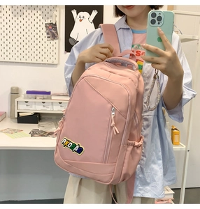 Lifestyle view of pink nylon school backpack with RKOBAO patch in study room setting