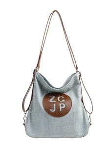 Versatile light grey canvas backpack with brown leather strap and round logo patch