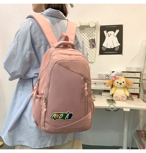 Rear view of a student pink nylon backpack with RKDBAG embroidery and multiple pockets