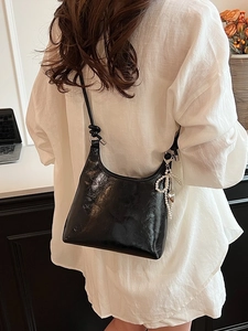 Fashionable black glossy leather shoulder bucket bag with pearl bow pendant detail