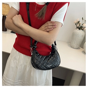Detail of black quilted half-moon bag with spherical handle and silver metal hardware