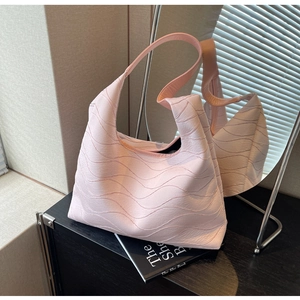 Detail shot of a pink tote bag featuring unique wavy pleats and an integrated shoulder strap