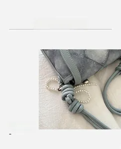 Detail of denim plaid bucket bag with braided knot handle and faux pearl chain