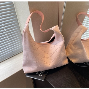 Macro detail of a light pink hobo bag with textured ripples and a wide shoulder strap