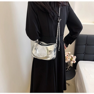 Dettaglio di una borsa a luna argento con tracolla a catena indossata da una modella