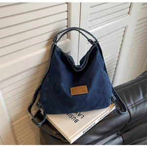 Dettaglio del denim blu scuro e della toppa in pelle marrone sulla borsa hobo capiente