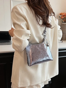 Silver metallic shoulder bag with pearl tassels and heart charm on a white blazer