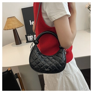 Detail view of black quilted leather crescent bag with metal chain and top handle