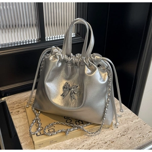 Détail du sac seau argenté avec fermeture à cordon et décoration de nœud métallique